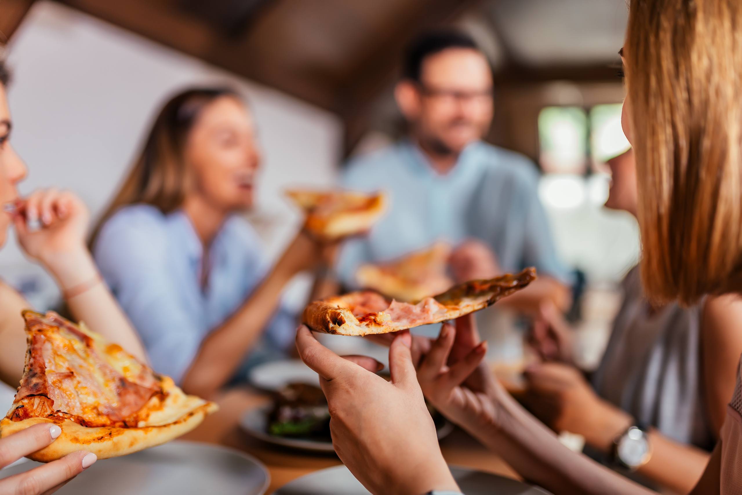 Eating pizza with friends. Close up.